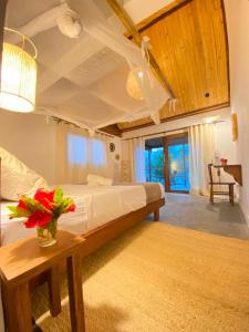 a bedroom with a bed and a table with flowers on it at ANKAVIA Lodge in Toamasina