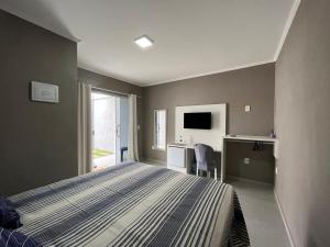 a bedroom with a bed and a desk and a television at Pousada Recanto Sossego in Saquarema