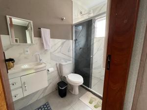a bathroom with a toilet and a shower and a sink at Pousada Recanto Sossego in Saquarema