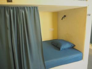 a bed in a room next to a curtain at Funky Monkey Surfhostel Hiriketiya in Hiriketiya