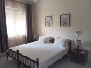 a bedroom with a large white bed and a window at Lalas ASA in Praia