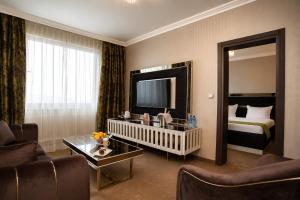 a hotel room with a bed and a living room at Astoria Grand Hotel in Sofia