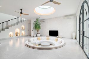 a white living room with a white couch and a tv at Casa Contenta Canggu - Luxury 5BR Private Pool Villa in Canggu