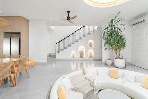 a living room with white furniture and a staircase at Casa Contenta Canggu - Luxury 5BR Private Pool Villa in Canggu