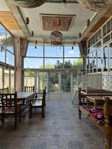 a room with a table and benches and windows at Гостевой дом Sartepo in Samarkand