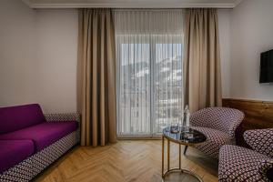 a living room with a purple couch and a glass table at Hotel Völserhof - Bergbahn im Sommer 2026 inklusive in Bad Hofgastein