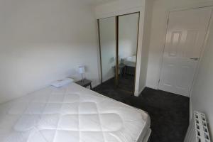 a bedroom with a large white bed and a mirror at Glasgow West End Accommodation in Glasgow
