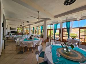 a restaurant with white tables and chairs and windows at Gassy Country House Ivato Airport in Ivato