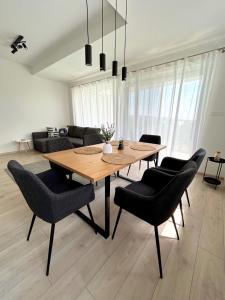a living room with a wooden table and chairs at Helikon Terasz Apartman in Keszthely