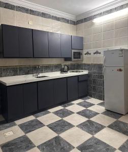 a kitchen with black cabinets and a white refrigerator at شقة لك بالكامل in Taif