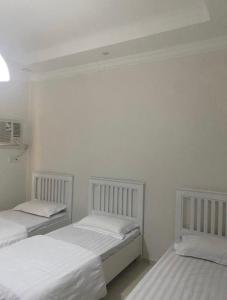 two beds in a room with white walls at شقة لك بالكامل in Taif