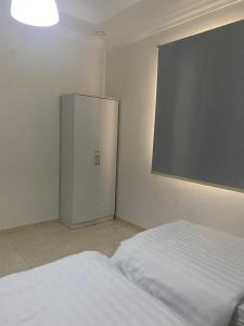 a bedroom with a white bed and a cabinet at شقة لك بالكامل in Taif