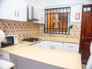 a kitchen with white cabinets and a microwave and a window at Queen Tori in Malindi