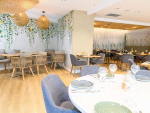 a dining room with tables and chairs and a wall with flowers at ibis Styles Tours Centre in Tours