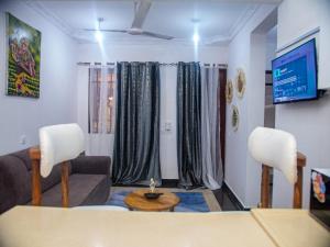 a living room with a couch and chairs and a tv at Queen Tori in Malindi