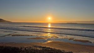 a sunset on a beach with the ocean at Refúgio dos Guaiás - Apart Hotel in Bombinhas
