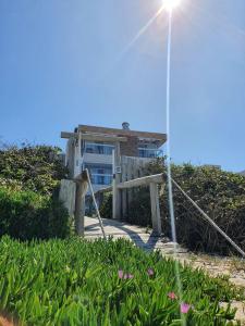 a house on the beach with a wooden gate and flowers at Refúgio dos Guaiás - Apart Hotel in Bombinhas