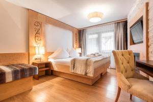 a hotel room with a bed and a chair at Hotel Albona in Ischgl