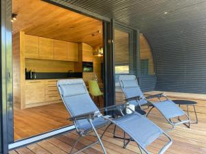 three chairs sitting on a porch with a kitchen at Wellness Chalet unterm Trifels in Annweiler am Trifels