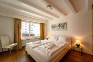 a bedroom with a large white bed and a window at Slope-Side Mountain Apt Sleeps 4 in Laax +13 photos