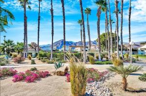 a garden with palm trees and flowers at Desert Breezes Resort in Palm Desert