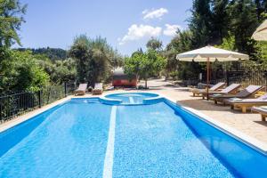 a swimming pool with chairs and an umbrella at Apanema Mindfulness, Relaxing Adults Only Resort, Fast WiFi, Pool, Sauna, Massage in Asprogerakata