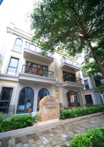a large white building with a tree in front of it at Maison Thu in Phú Quốc