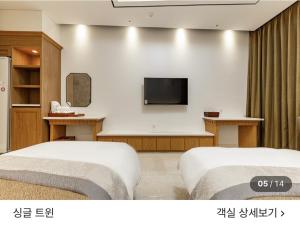a room with two beds and a flat screen tv at 호텔뷰 in Tomin-dong
