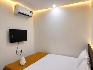 a bedroom with a white bed and a tv on the wall at Global Residency in Palakkad