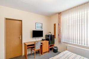 a bedroom with a desk with a computer and a television at Hotel Zum Wikinger in Dornum