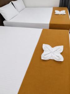 two beds with white sheets with white bows on them at Global Residency in Palakkad