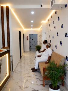 three men sitting on a couch in a living room at Global Residency in Palakkad