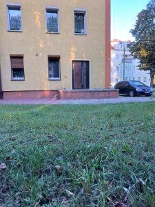 a building with a grass field in front of it at Louis Apartaments Kostrzyn in Kostrzyn nad Odrą