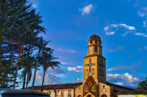 a clock tower on top of a building with palm trees at hostal combi in Salento