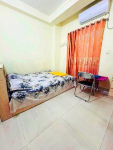 a bedroom with a bed and a chair in it at Ast Guest House in Dhaka