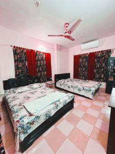 two beds in a room with red curtains at Ast Guest House in Dhaka