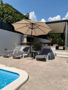 a group of chairs and an umbrella next to a pool at Apartments Antini in Solin