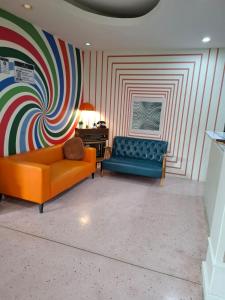 a living room with an orange couch and a striped wall at Happy 2 Pratunam Hotel in Bangkok