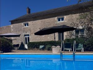 a pool with an umbrella and chairs and a building at Domaine la Boulinière - La Biche in Journet