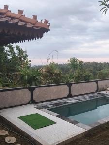 a swimming pool with a green mat next to a balcony at Prima Eco Cabin in Pabean Buleleng