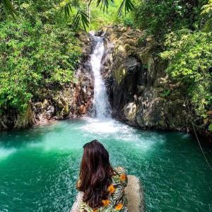 a woman sitting on a rock in front of a waterfall at Prima Eco Cabin in Pabean Buleleng +10 photos