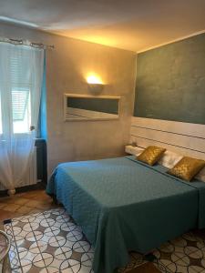 a bedroom with a blue bed and a window at Marieta Rooms in Sarzana