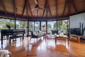 a living room with a piano and a couch at The Graceful Dodeca Treehouse Coalcliff 