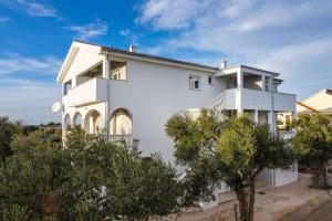 a white house with trees in front of it at Apartment Paulo&Lorenco in Sveti Filip i Jakov