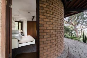 a bedroom with a bed and a brick wall at The Graceful Dodeca Treehouse Coalcliff 