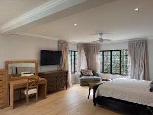 a bedroom with a bed and a desk and a television at Upper Constantia Entertainers dream! in Cape Town +47 photos