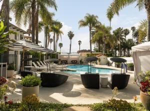 a pool with chairs and umbrellas and palm trees at The Milo in Santa Barbara