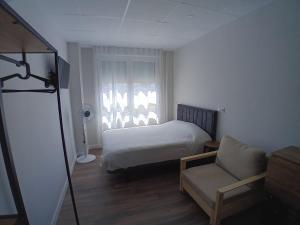 a bedroom with a bed and a chair and a window at Morgan Apartments Bilbao in Bilbao
