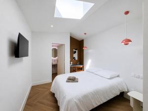 a white bedroom with a bed and a television at Les Henrions in Pierrelatte
