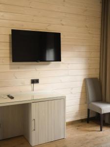 a tv on a wall with a desk and a chair at Sunrise Hotel in Kyiv
